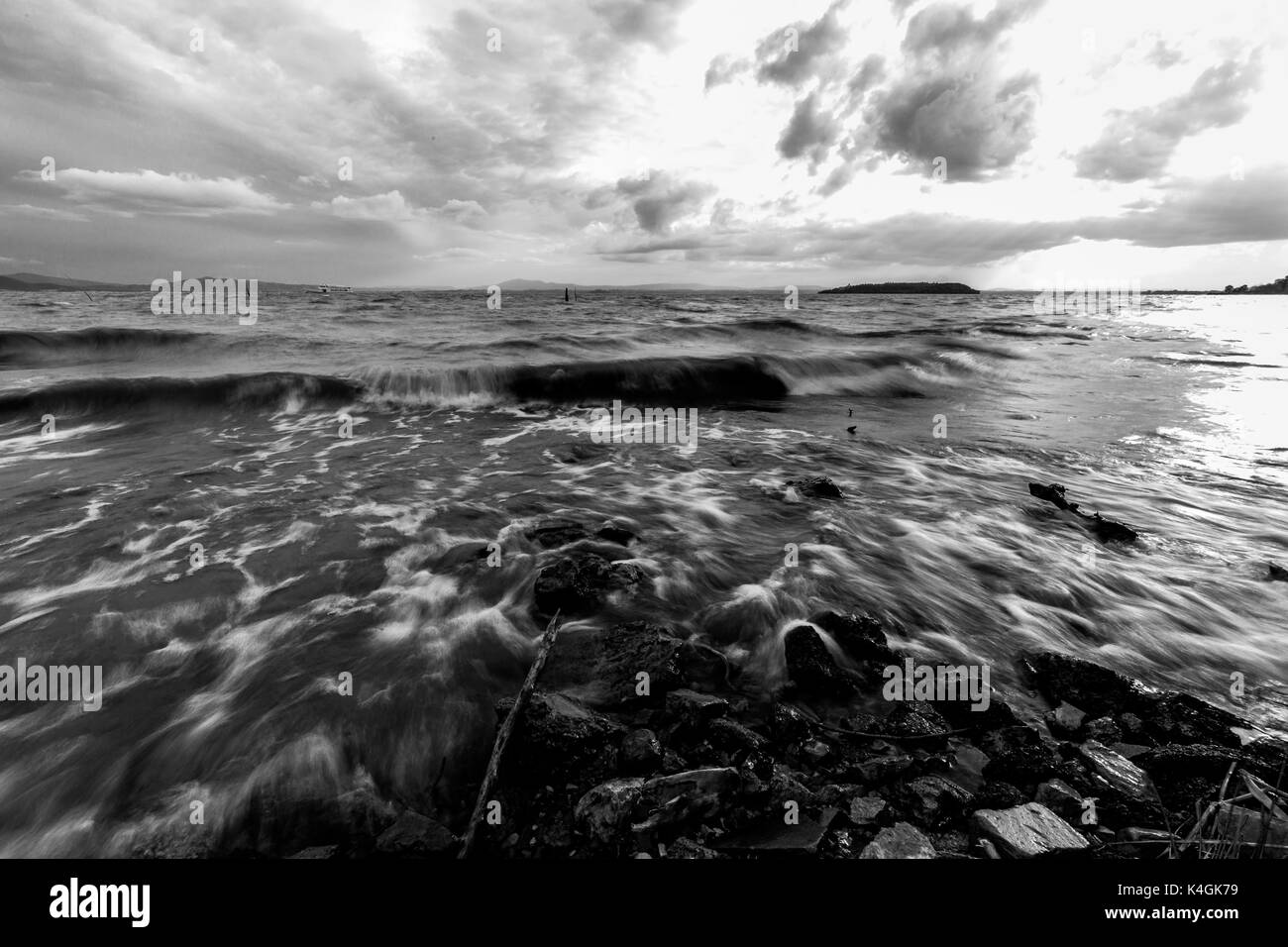Close view of a lake shore with water moving fast on rocks and stones Stock Photo