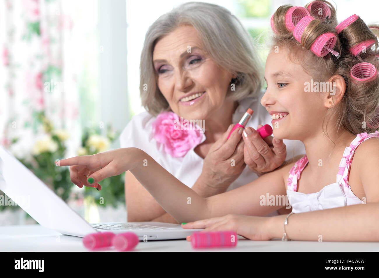Cute little girl in hair curlers with granny using laptop at home Stock ...