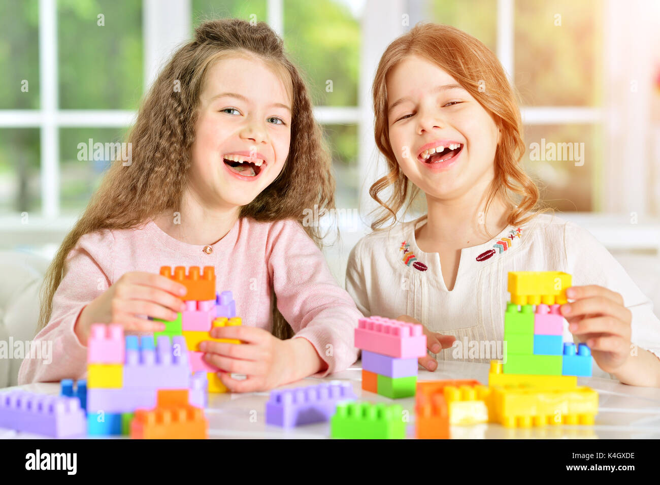 Two cute little girls playing with colorful plastic blocks Stock Photo ...