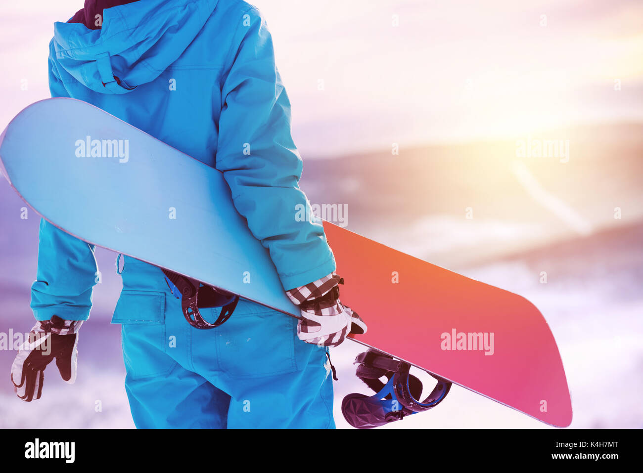 Woman holding snowboard in hands. Closeup view. Snowboarder or snowboarding concept at sunrise or sunset time Stock Photo