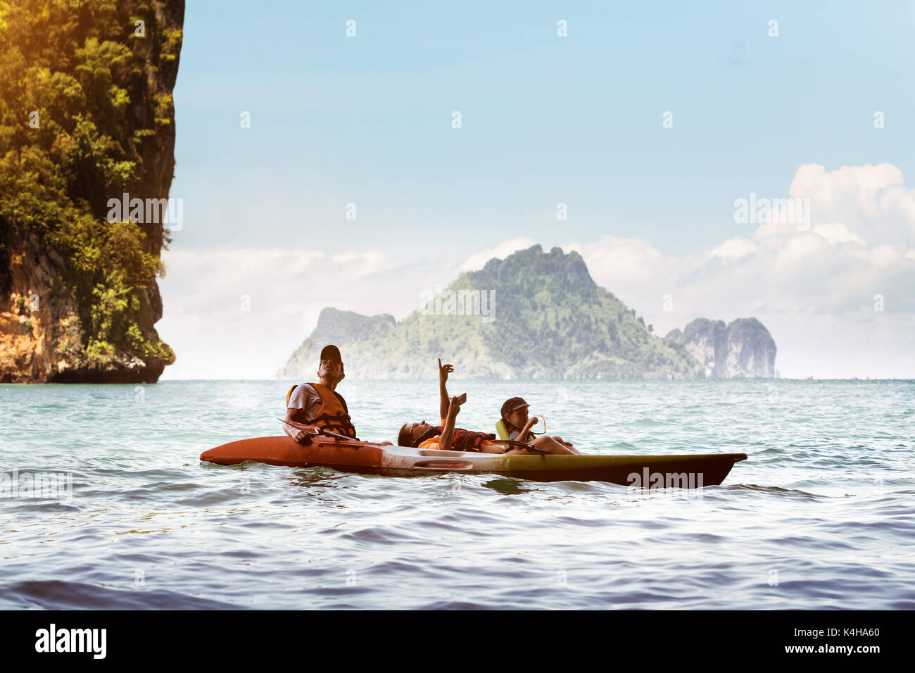Happy family of father mother and son kayaking at sea bay under big rocky islands. Krabi province, Thailand. Space for text Stock Photo