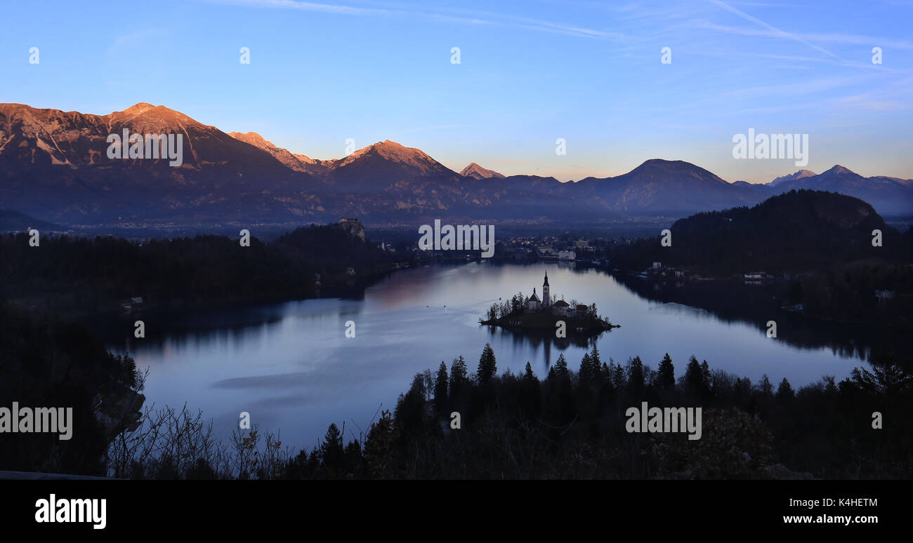 A panorama of the island of Bled with the Assumption church amidst forest and mountains. Stock Photo