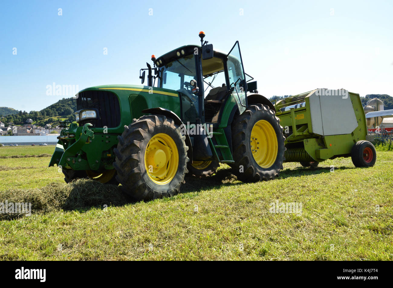 An agricultural tractor with a baler to harvest straw and hay. (Straw and hay bales) Stock Photo