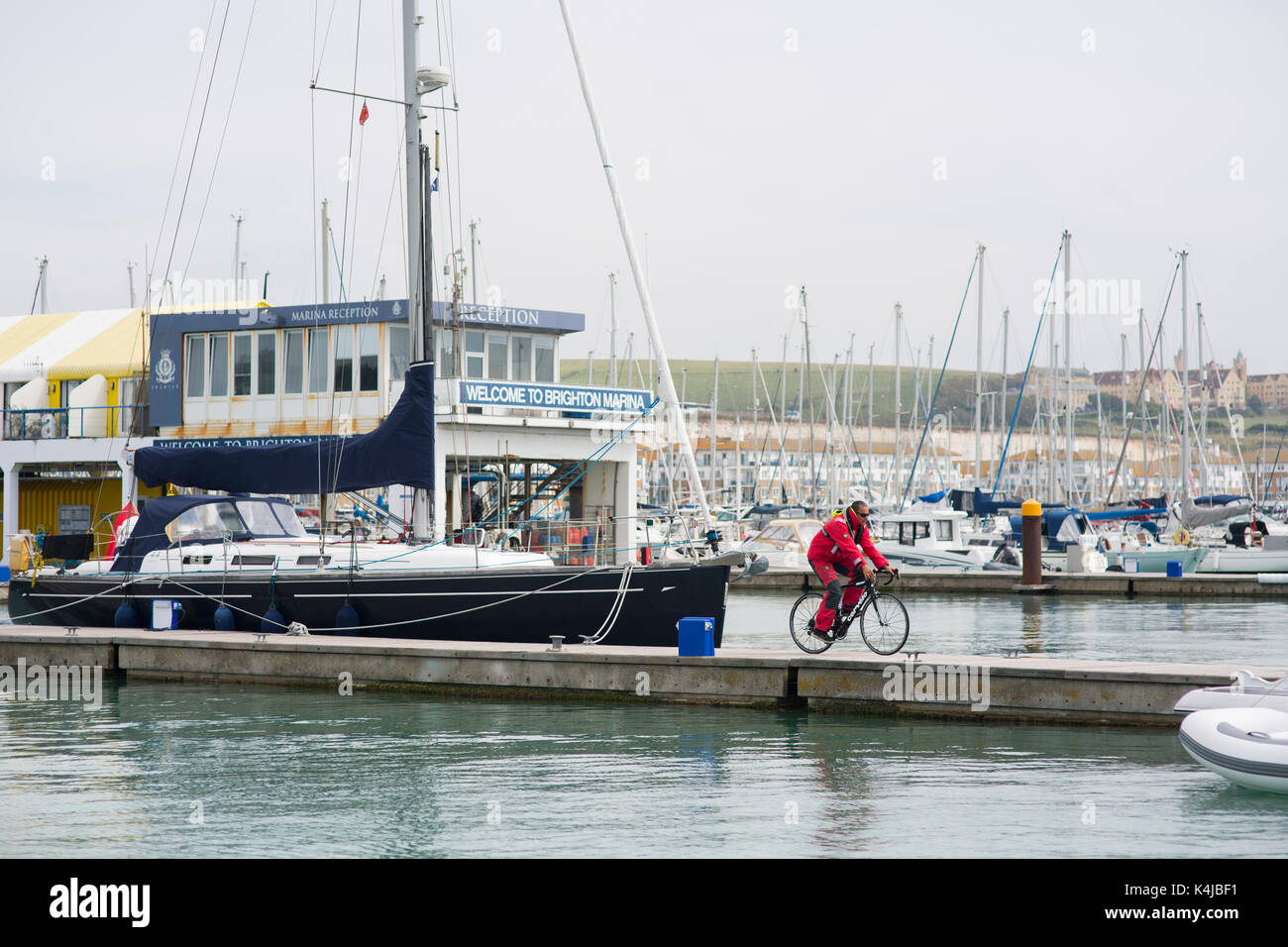 Cycling in the marina of Brighton with a  sailing suit. Stock Photo