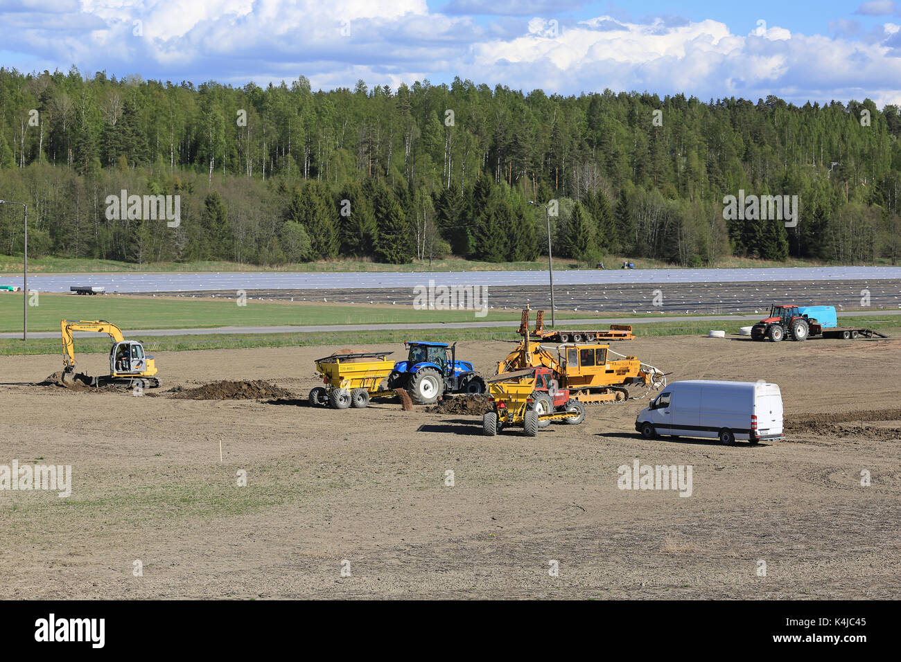 SALO, FINLAND - MAY 26, 2017: View to a work site for installing modern agricultural drainage system on a field with equipment and workmen in action o Stock Photo