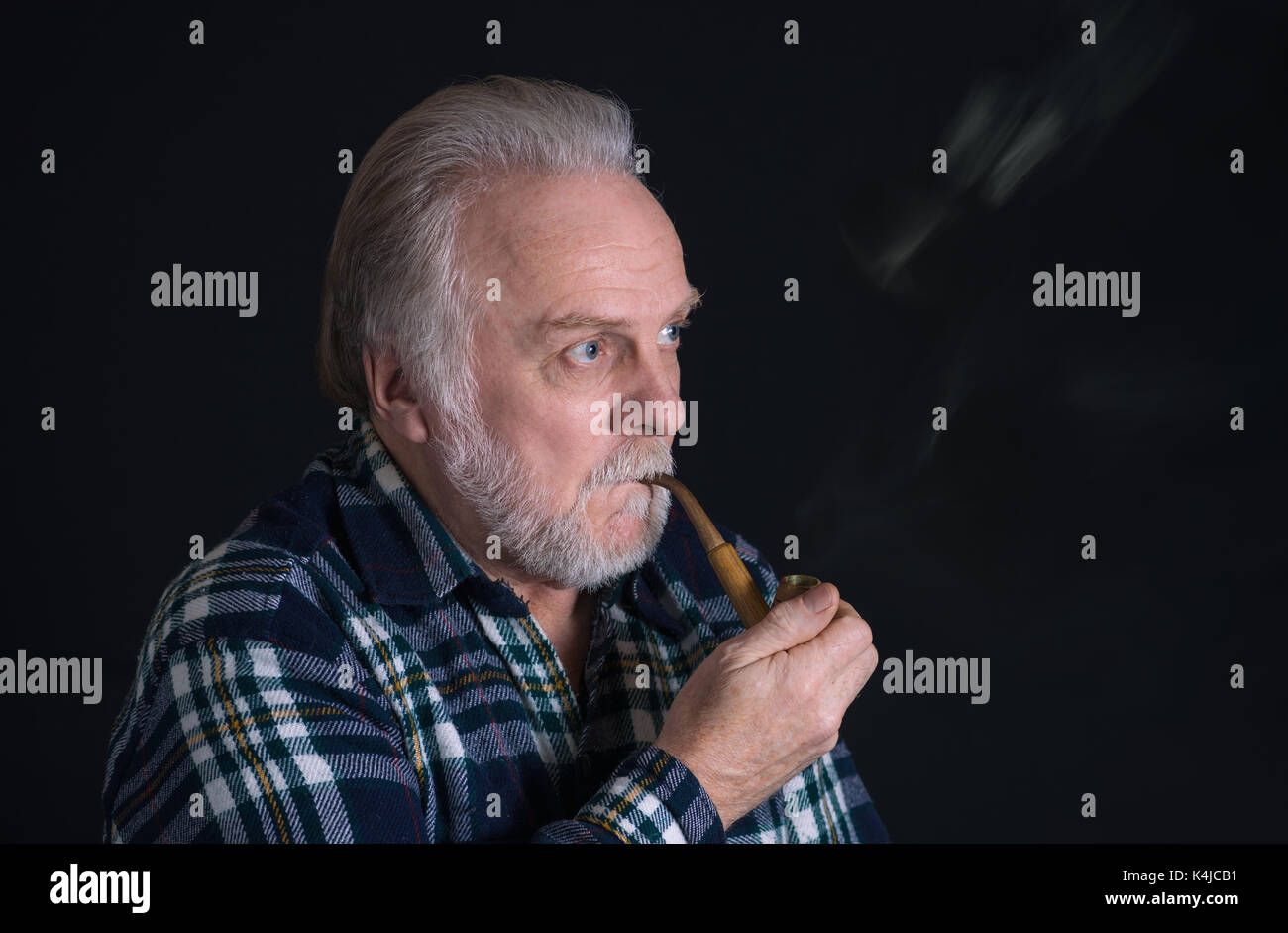 Portrait of a grey-haired, bearded Caucasian senior with tobacco pipe Stock Photo