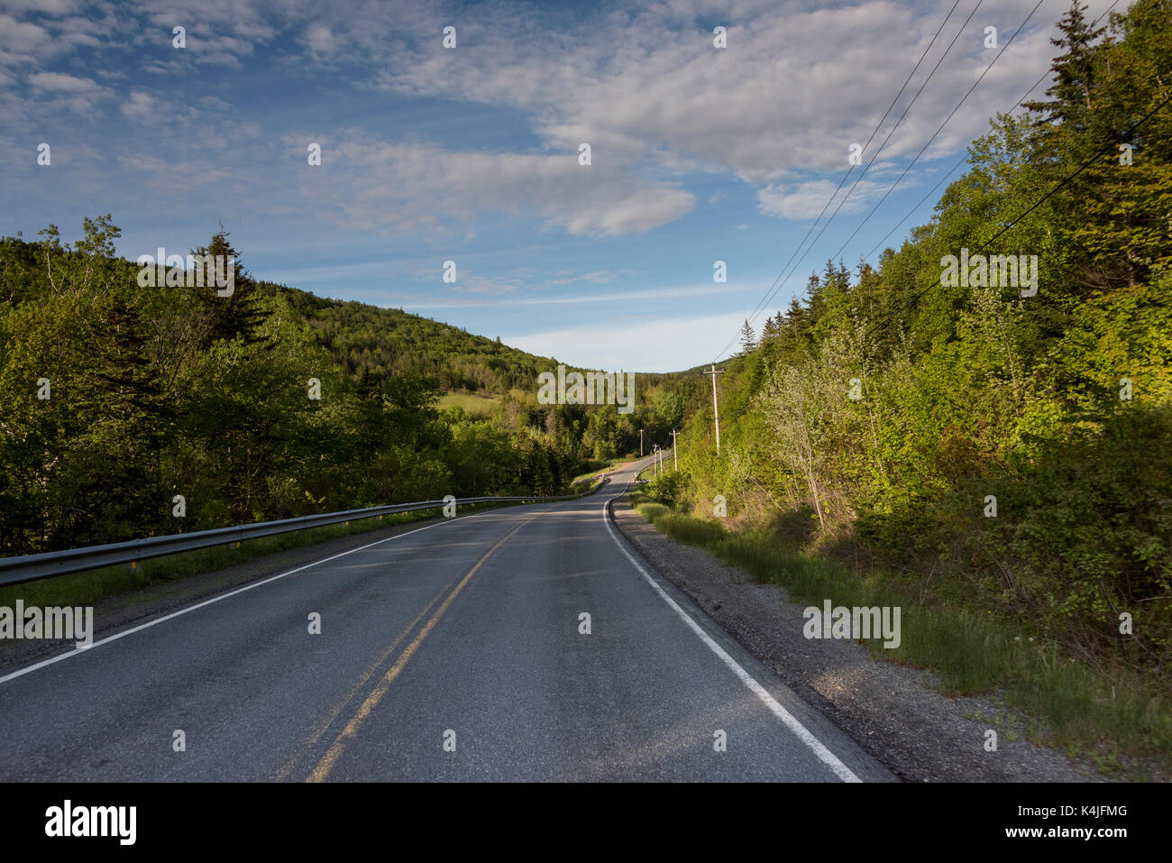 Empty road amidst trees by hills, Ceilidh Trail, Cape Breton Island, Nova Scotia, Canada Stock Photo