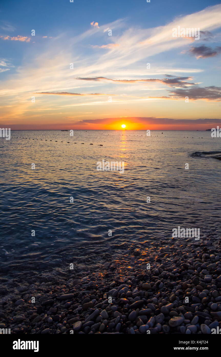 Summer sea sunset on the pebble beach, the sun, waves and clouds ...