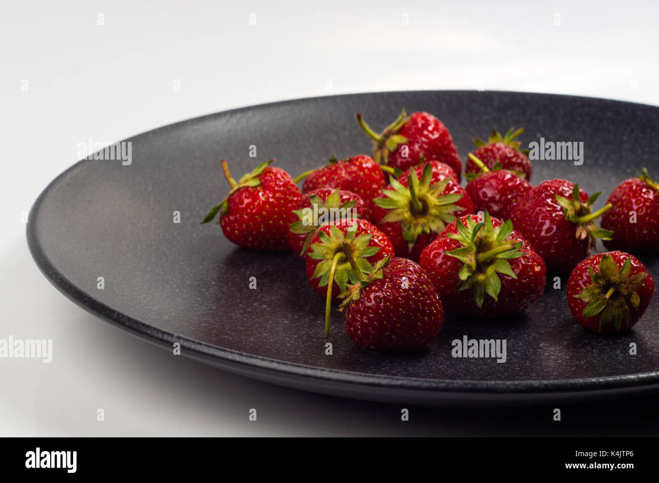 fresh ripe berries strawberries on black ceramic plate on white ...