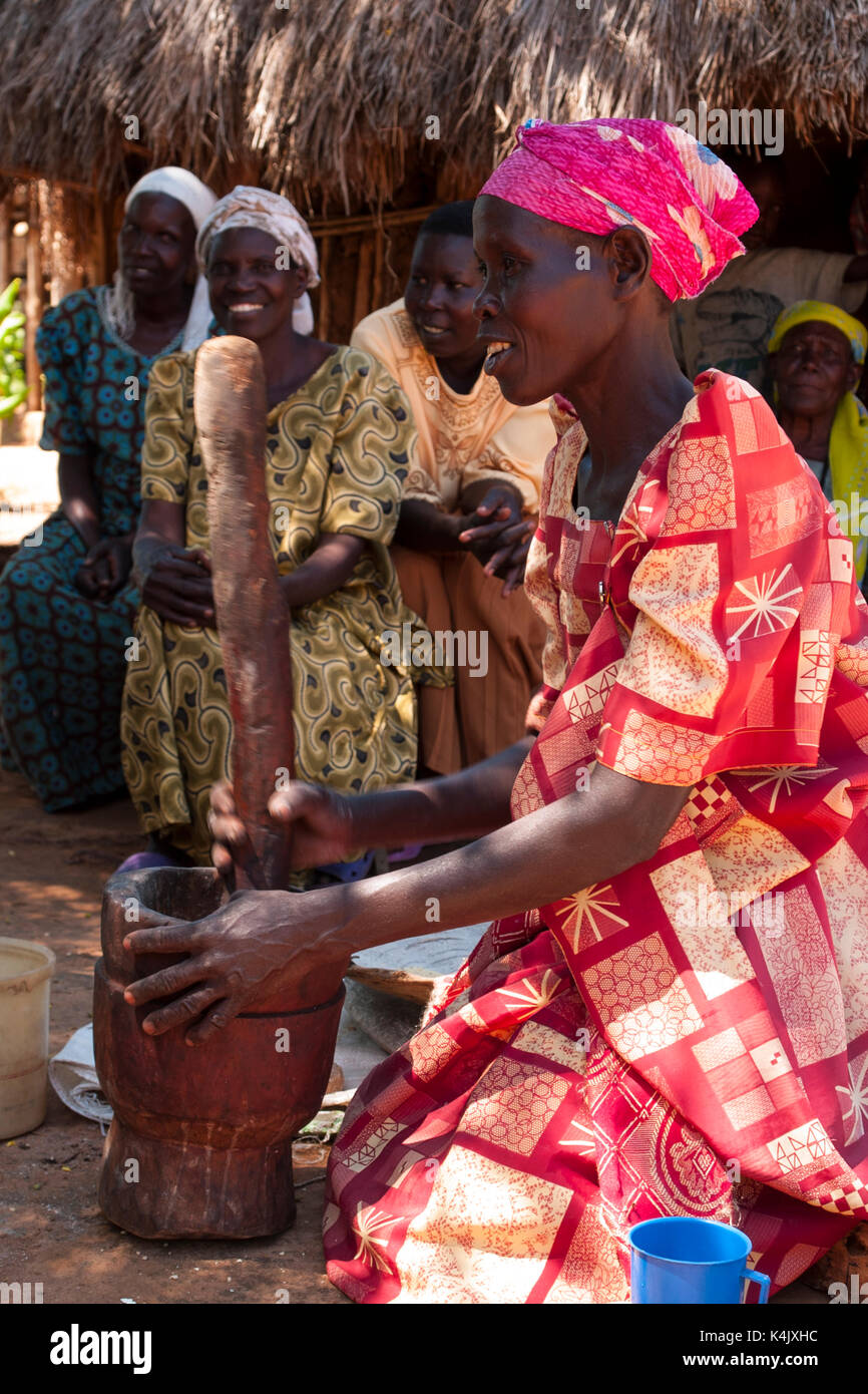 A woman pounding millet using a traditional wooden pestle and mortar at