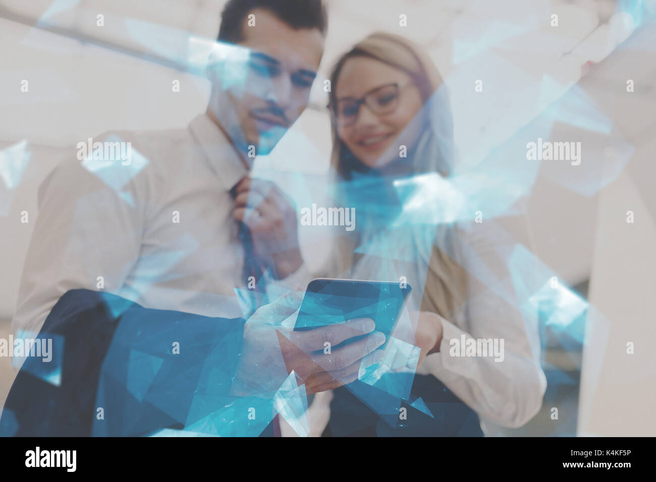 Young successful businesspeople using tablet in office, blue glowing polygons, depth of field Stock Photo