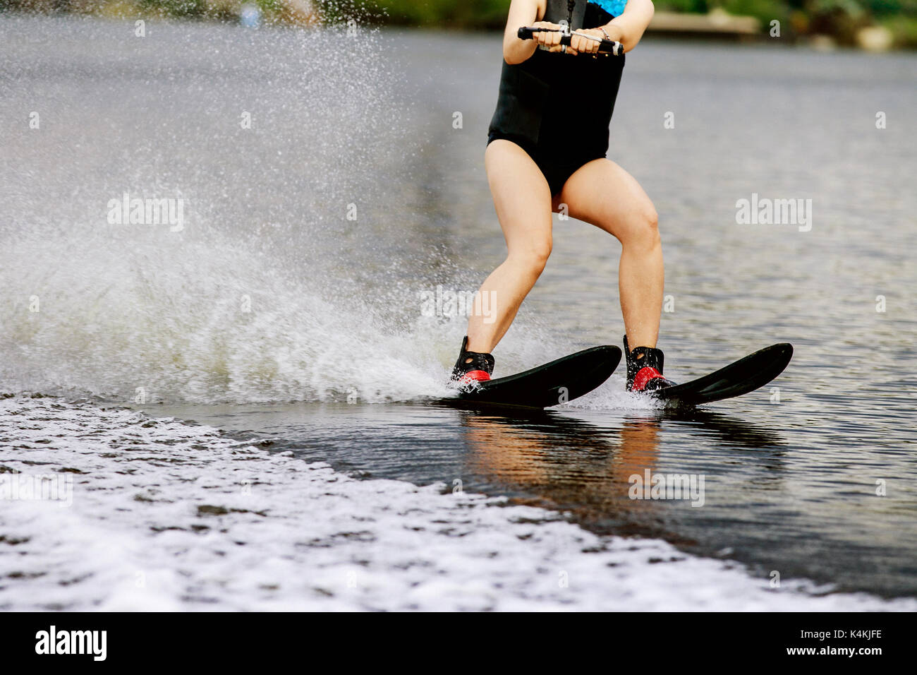 young woman on water ski rides on lake water spray Stock Photo