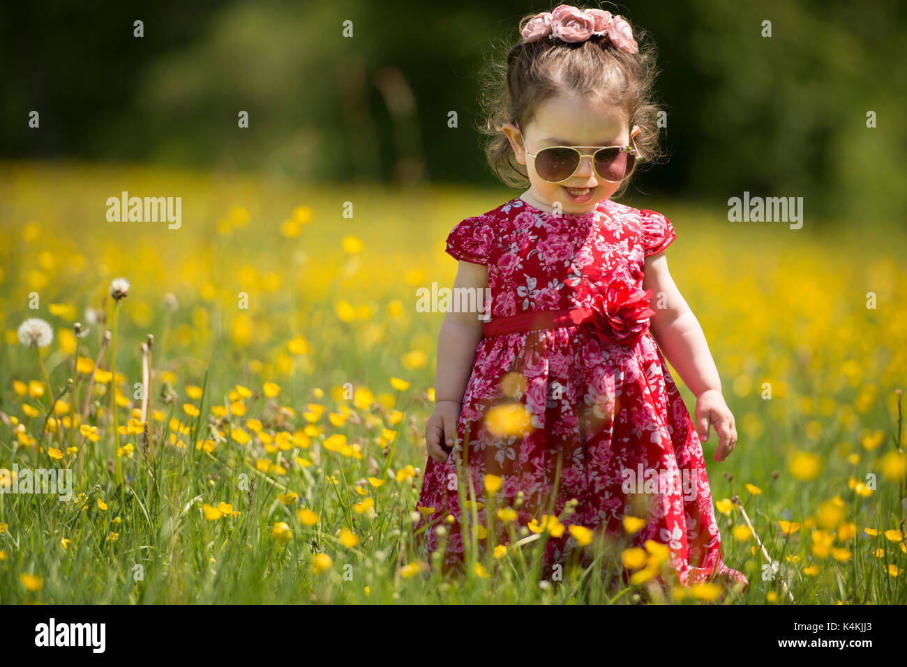 Young girl playing in a field wearing sun glasses and a red dress. credit Lee Ramsden / ALAMY Stock Photo