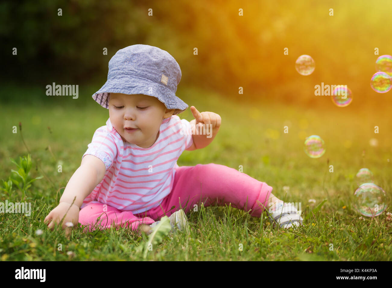 Adorable baby girl playing with grass; soap bubbles from bubble ...