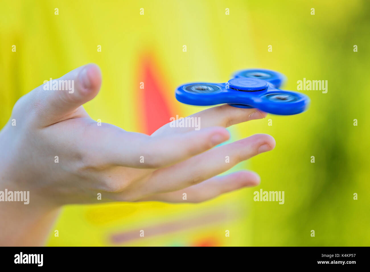 Girl's hand holding a spinning fidget spinner in her hand, spinning them on her index finger Stock Photo