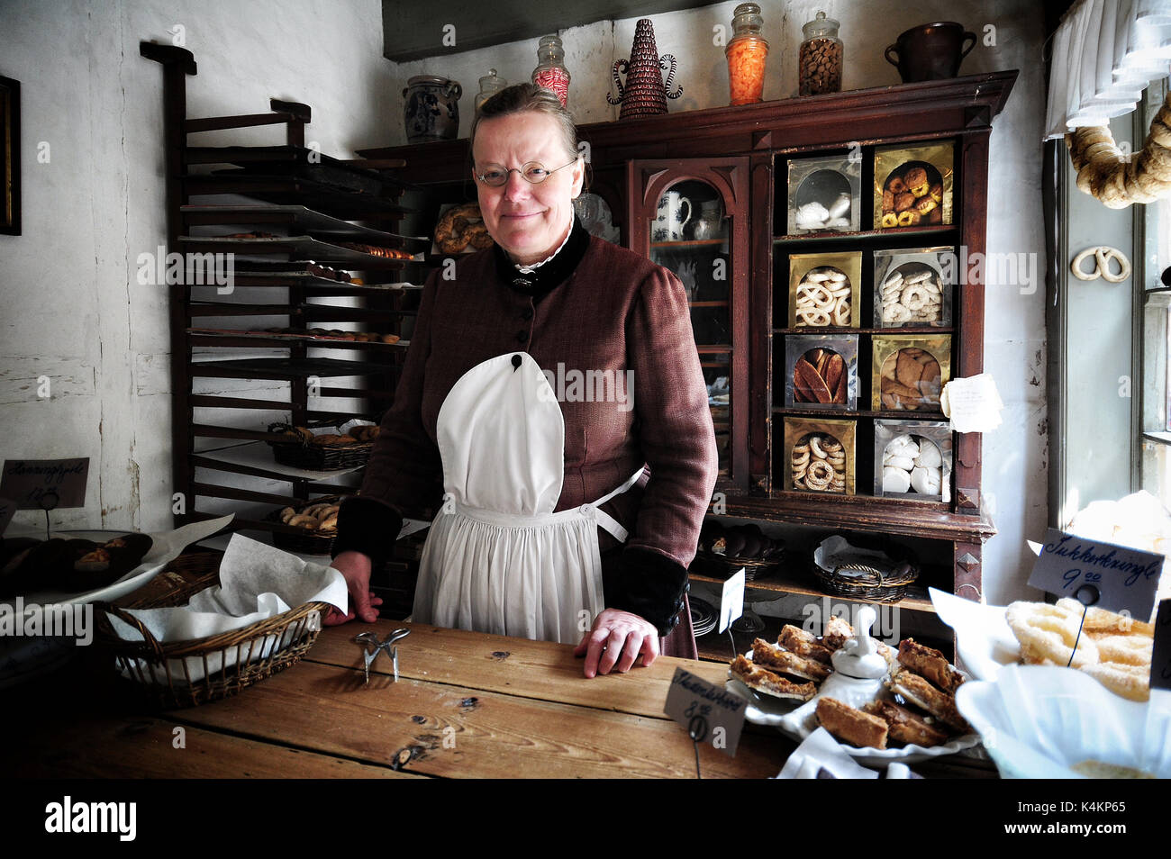 A woman in period costume sells Danish pastries in a shop at Den Gamle By, an open-air folk museum known in Aarhus, Denmark. Stock Photo
