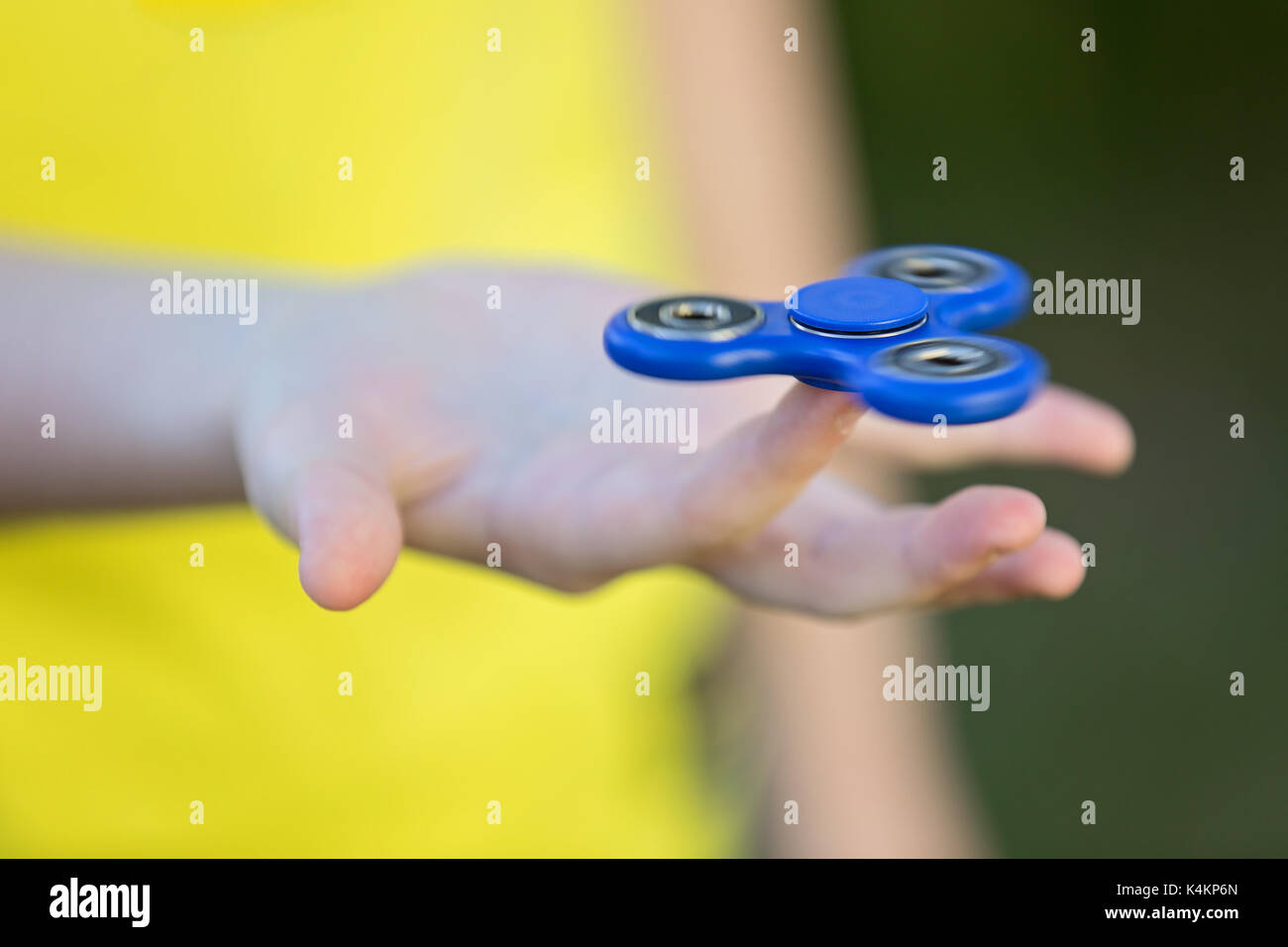 Girl's hand holding a spinning fidget spinner in her hand, spinning them on her index finger Stock Photo