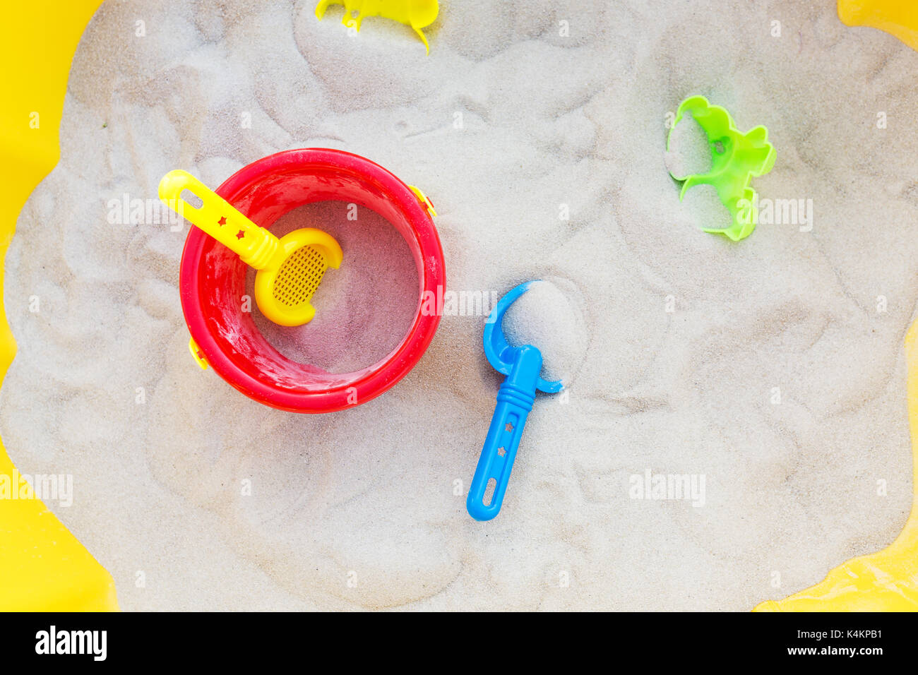 Plastic bucket, sifter and a small shovel in the sand; view from above