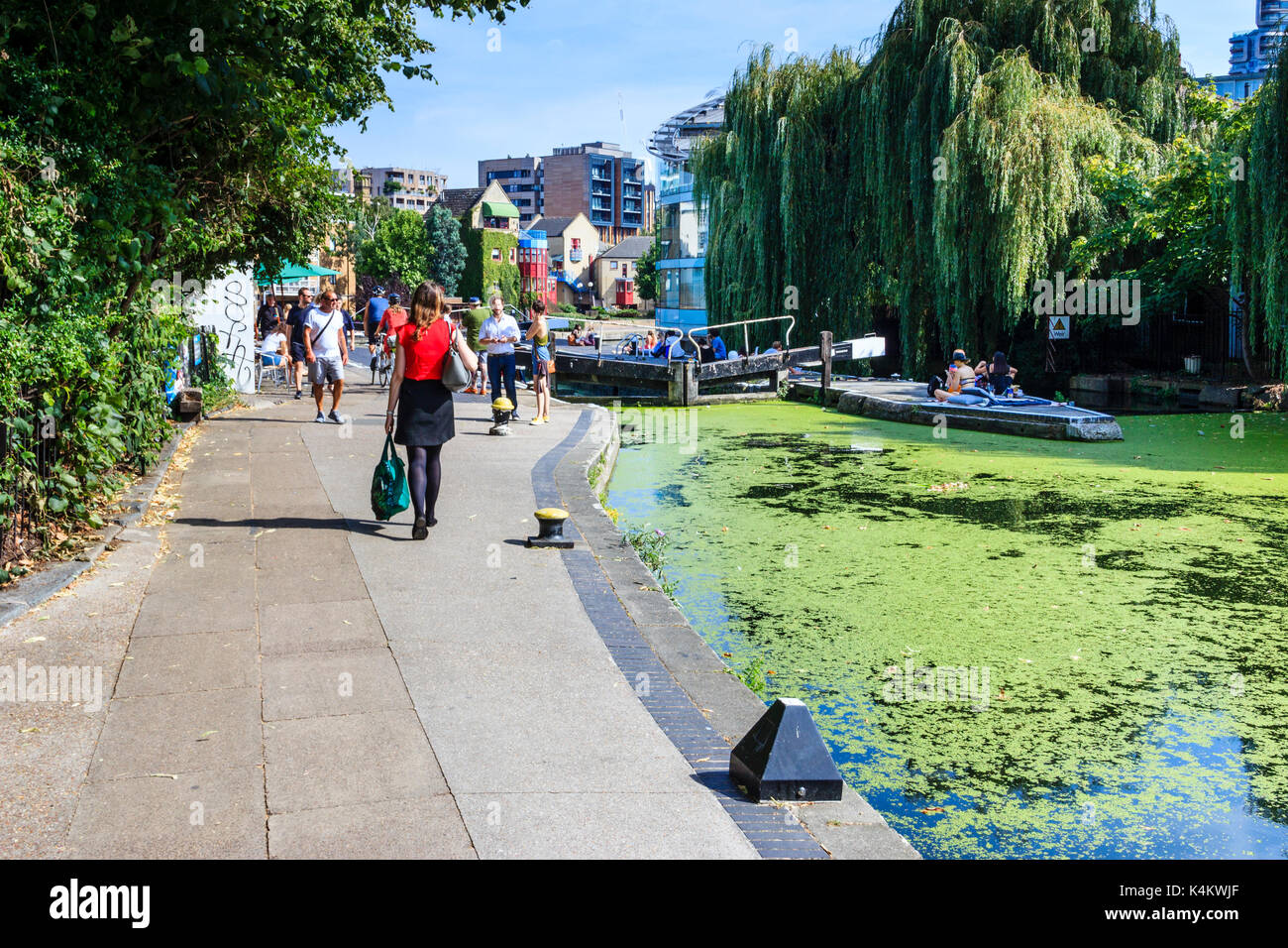 People basking in the sun and cooling off by City Road Lock as summer temperatures rise, Regent's Canal, Islington, London, UK Stock Photo