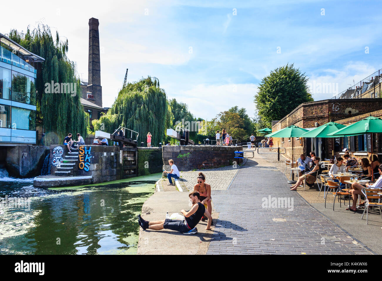 People basking in the sun and cooling off by the canal as temperatures rise, City Road Lock, Islington, London, UK Stock Photo
