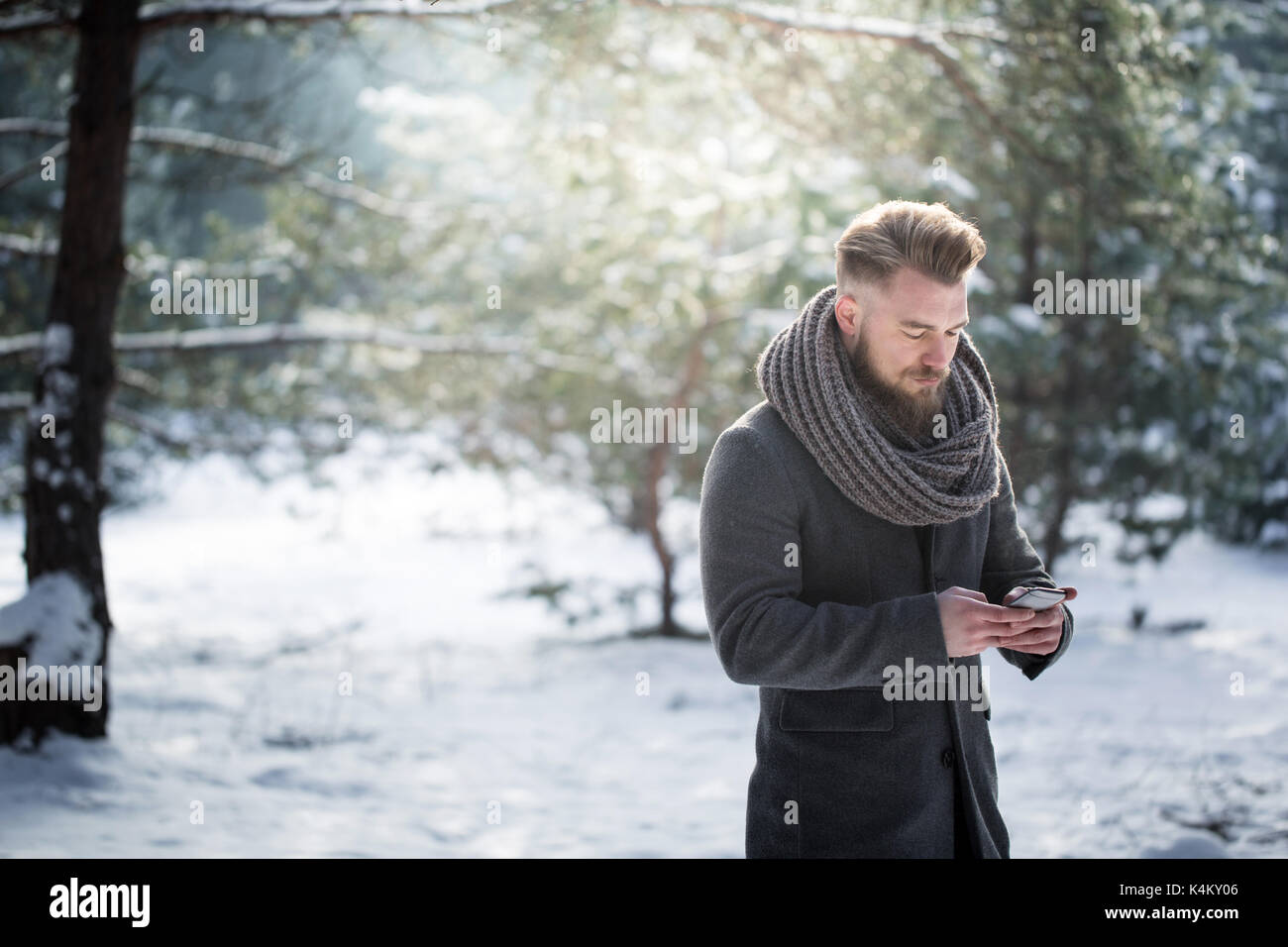 Man using his smartphone during winter forest walk Stock Photo