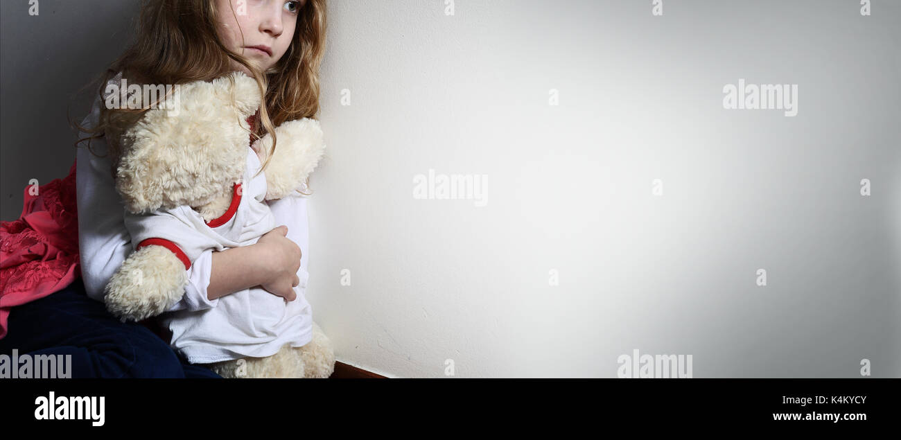 Frightened girl hugs a teddy bear Stock Photo