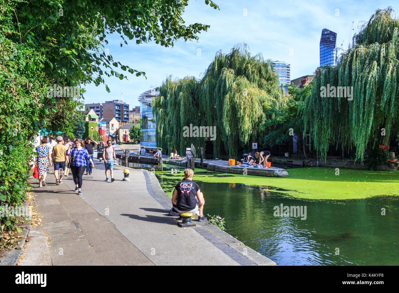 People basking in the sun and cooling off by City Road Lock as summer temperatures rise, Regent's Canal, Islington, London, UK Stock Photo