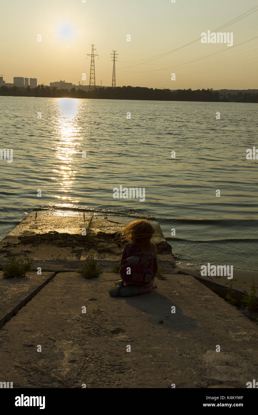 little girl sitting on the river bank Stock Photo - Alamy