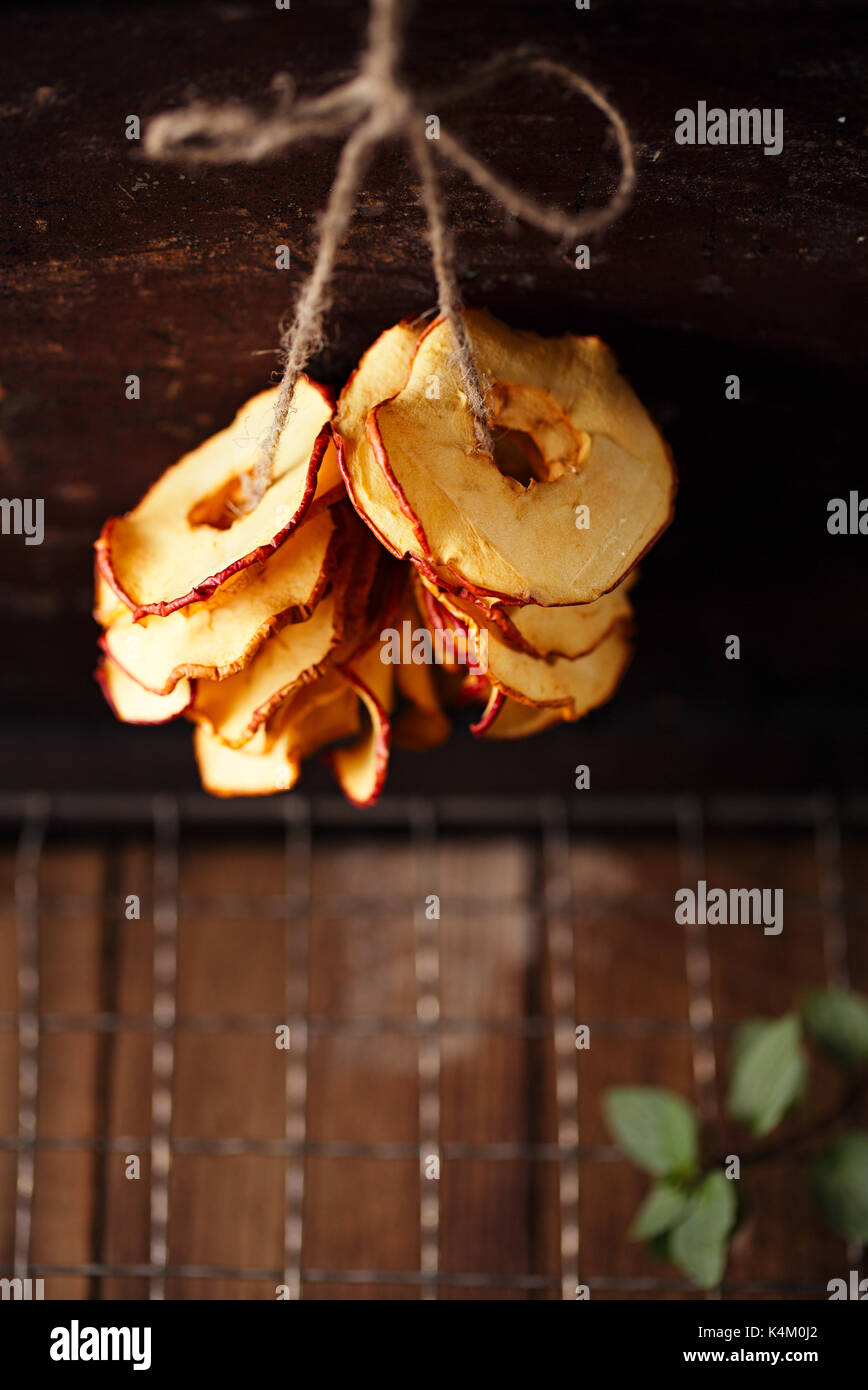 Dried apple slices hanging on string with dark metal backdrop and copy space Stock Photo