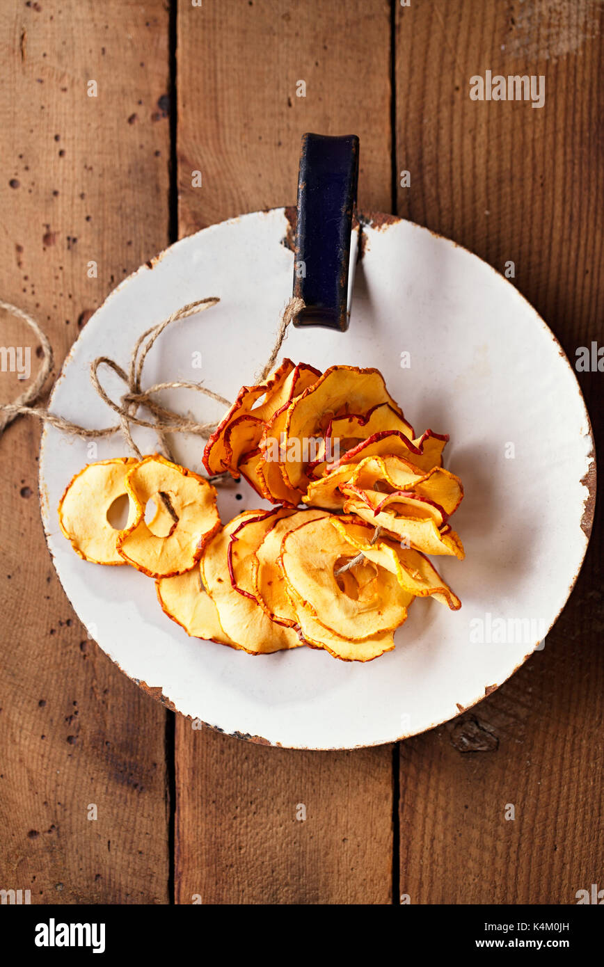 Dried apple slices on vintage enamelled dish and wooden background Stock Photo
