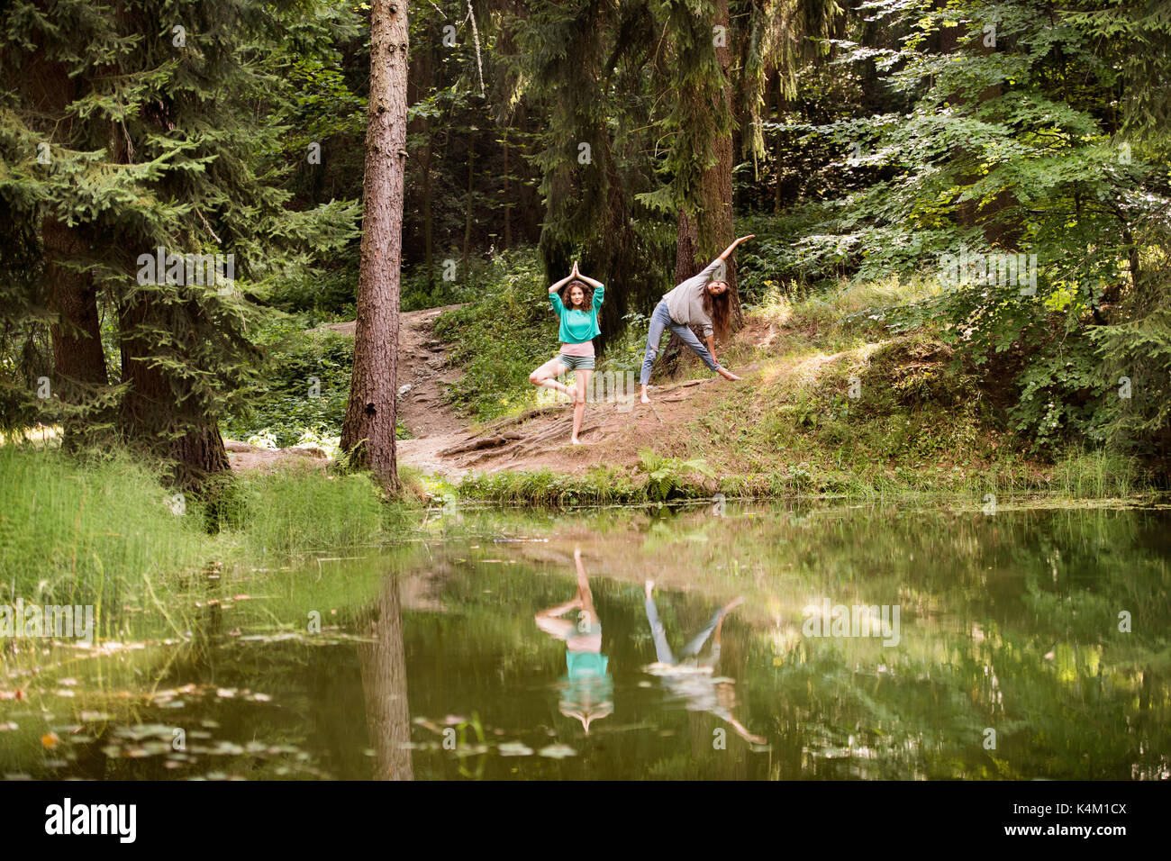 Teenage girls practice yoga at the lake in forest. Stock Photo