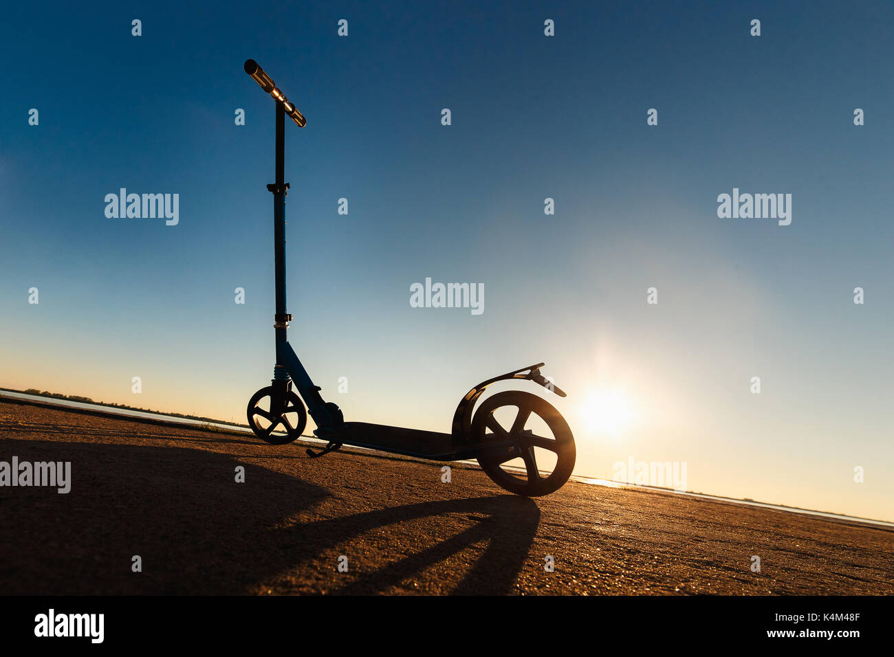 Kick scooter on asphalt running track , under sunlight at sunny summer