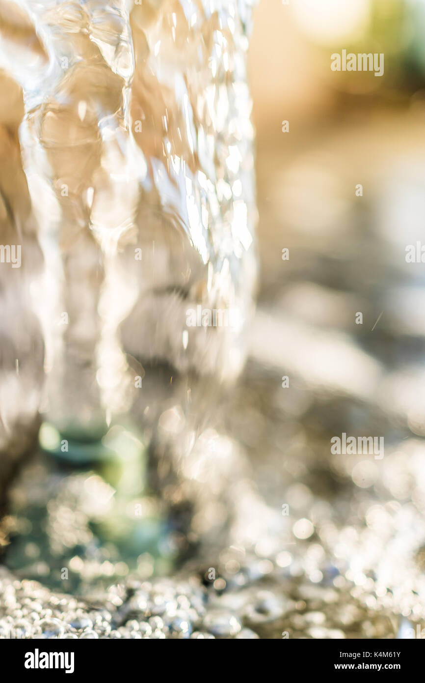 Detail macro close up of golden water fountain stream in park with