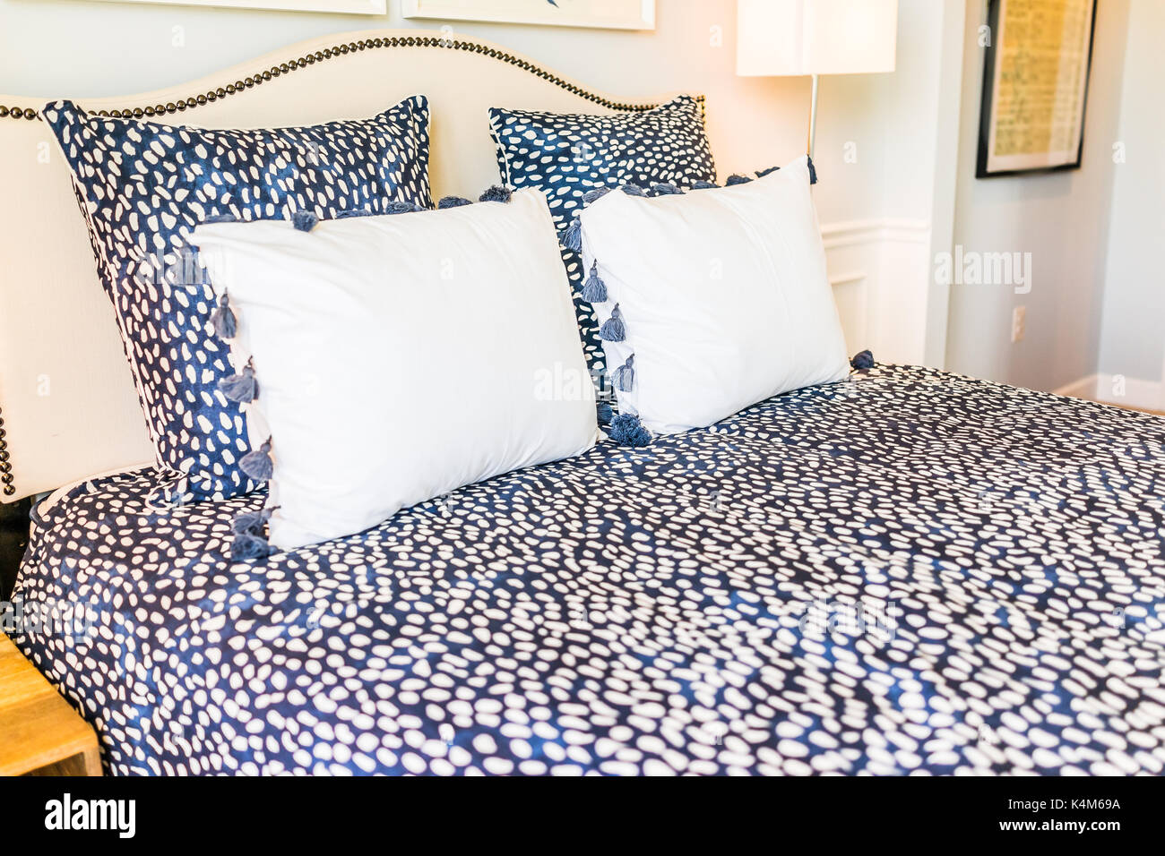 Closeup of new bed comforter with decorative pillows in bedroom in staging model home, apartment or house Stock Photo