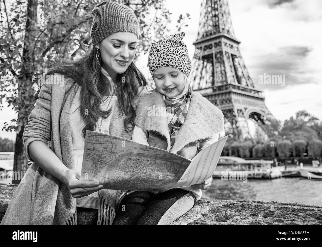 Autumn getaways in Paris with family. happy mother and daughter tourists on embankment near Eiffel tower in Paris, France looking at the map Stock Photo