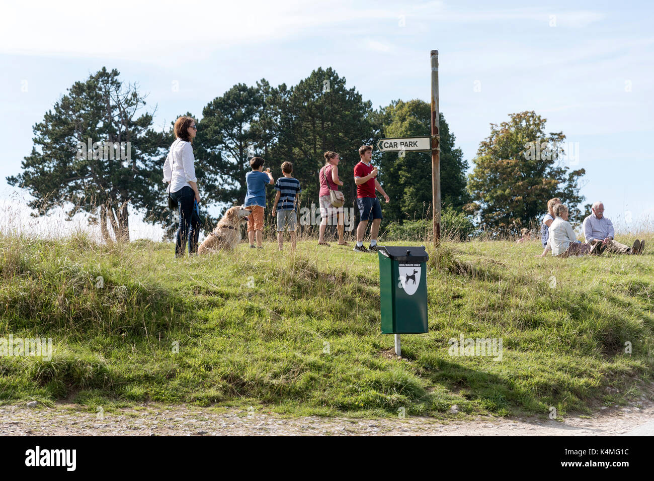 Visitors on Rodborough Common in the southern Cotswolds close to Stroud Gloucestershire England UK. In the foreground a dog waste bin Stock Photo