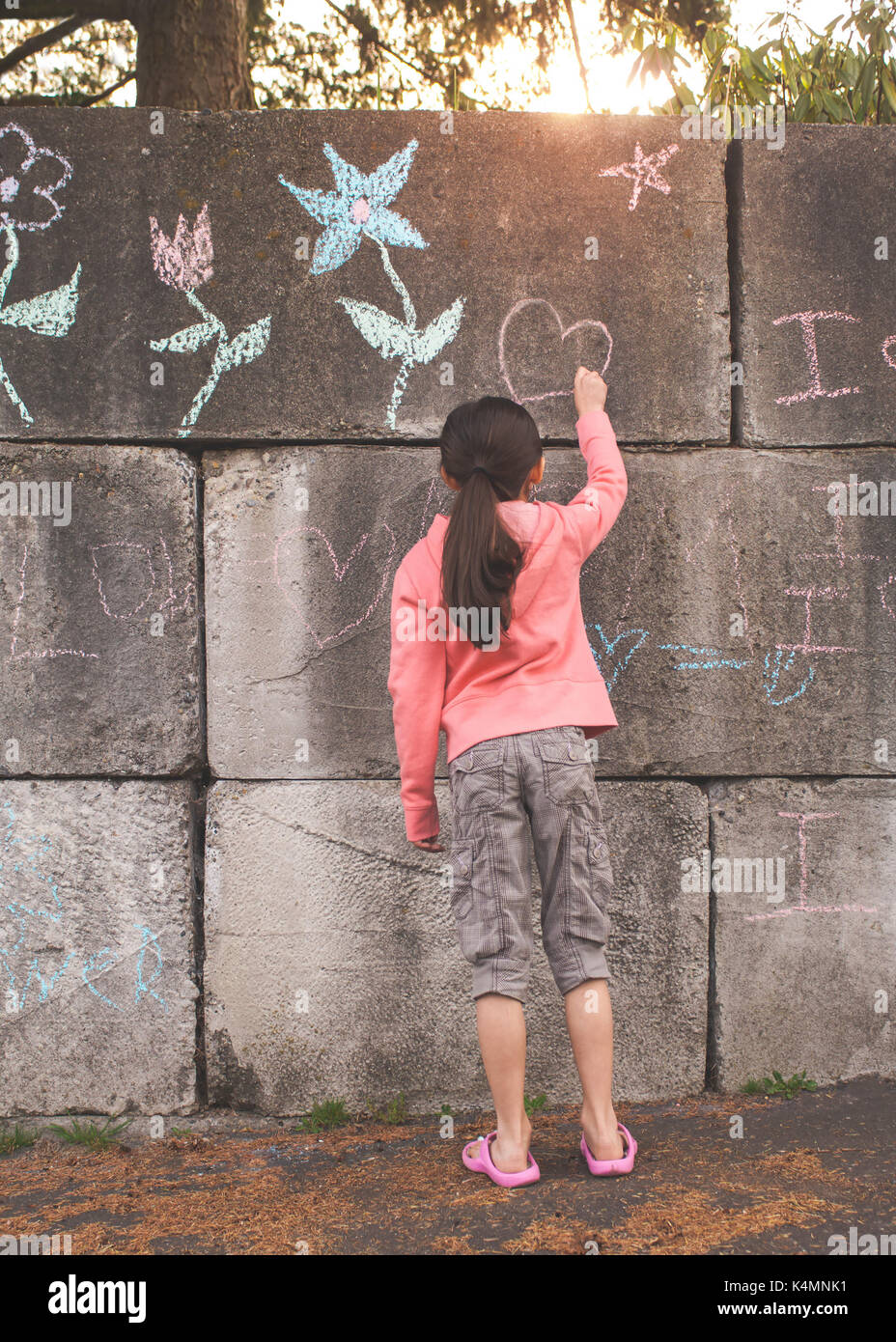 10 year old, little girl, elementary age, drawing and writing with chalk on concrete. Stock Photo