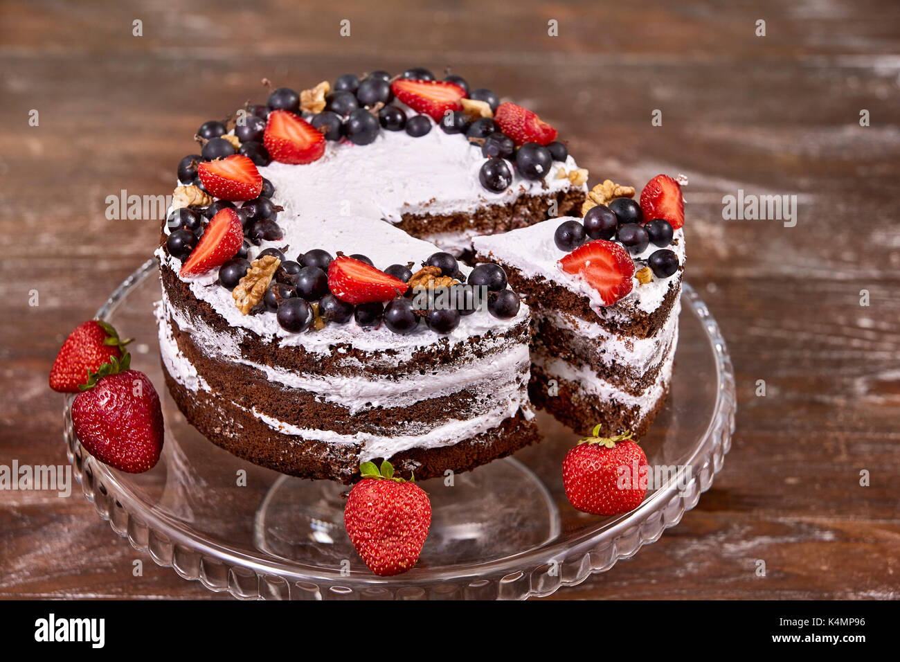 a cut of cake with whipped cream and strawberry fruits on wood table ...