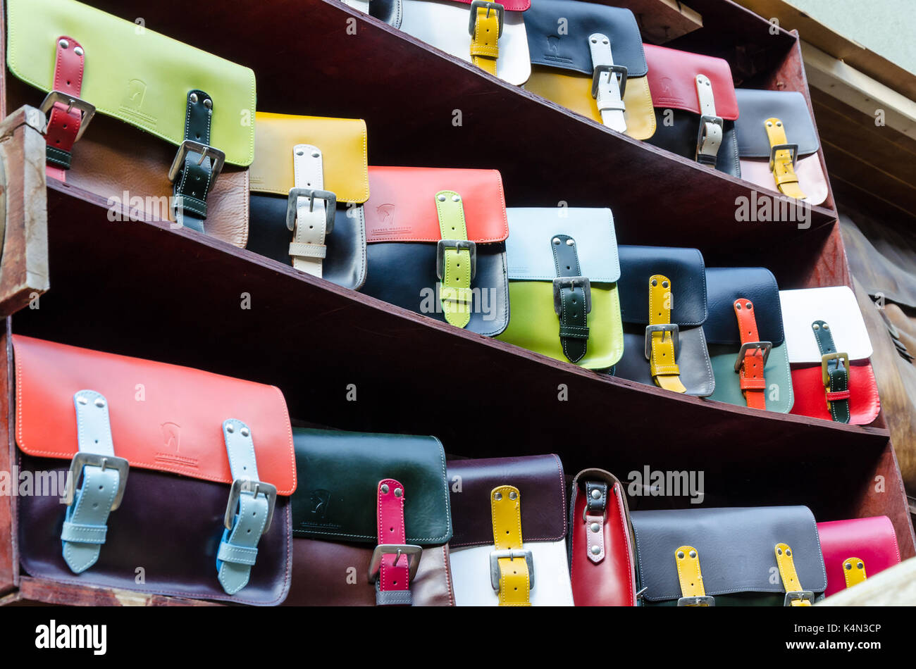 Colourful bags on display for sale on a shelf at a leather good manufacturer and retailer in the Camden market, London. Stock Photo