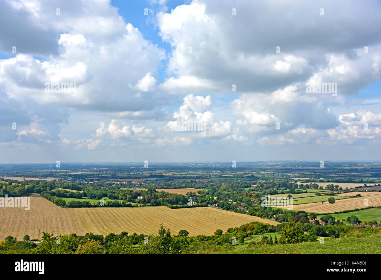 Chiltern Hills - view over Aylesbury Plain - harvested fields - woodland - hedgerows - blue haze horizon - cloud flecked blue sky Stock Photo