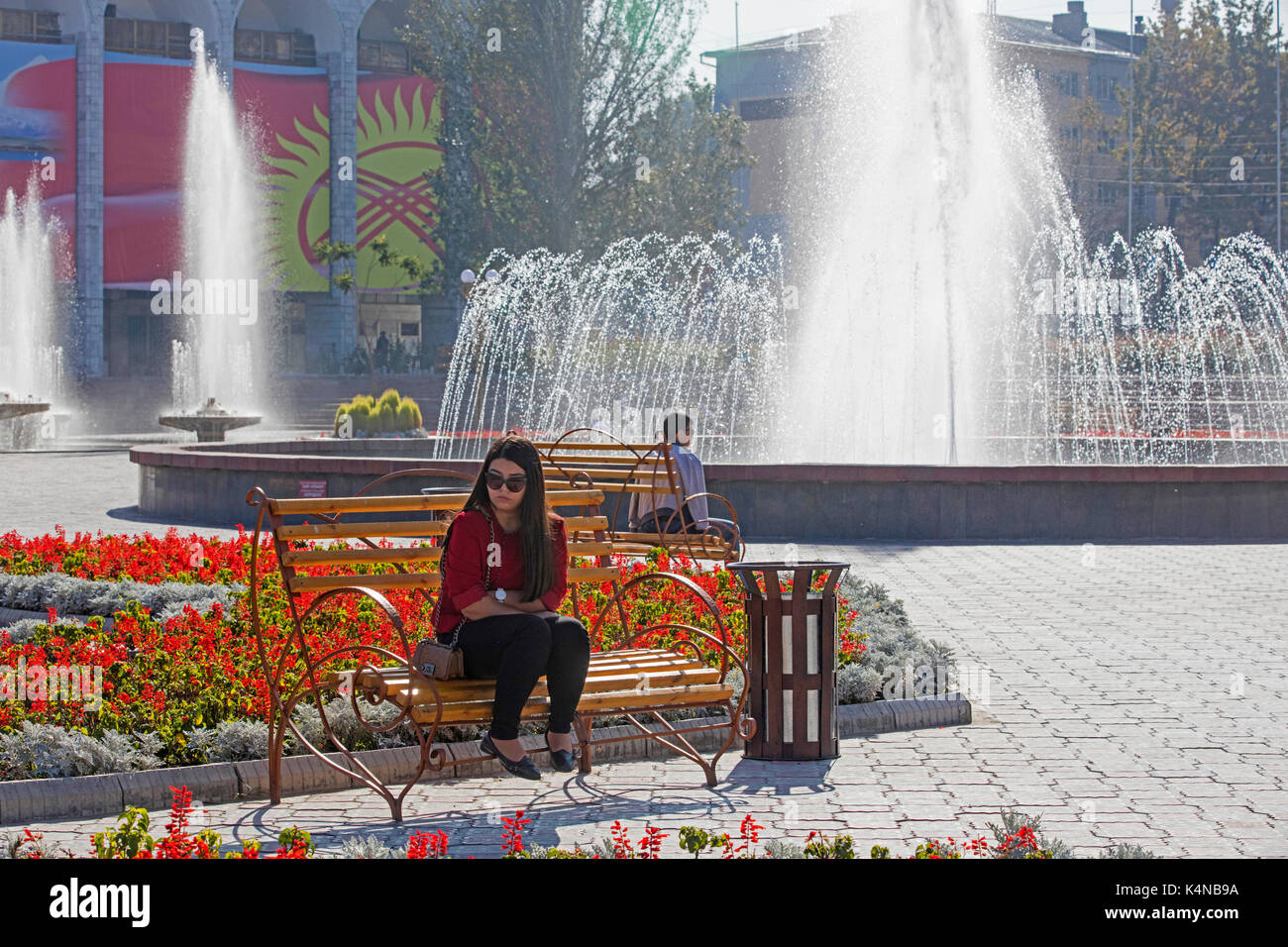 Fountain and Kyrgyz woman sitting in the Ala-Too Square in Bishkek, capital city of Kyrgyzstan Stock Photo