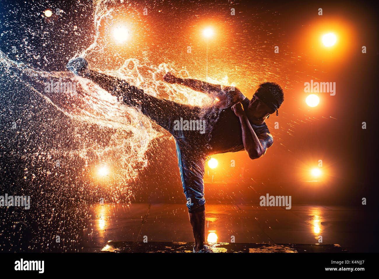 Young man break dancer making kick on splashing water. Tattoo on body. Stock Photo