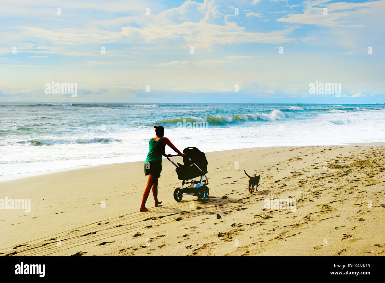 Woman with baby carriage and dog walking by the beach. Bali island, Indonesia Stock Photo