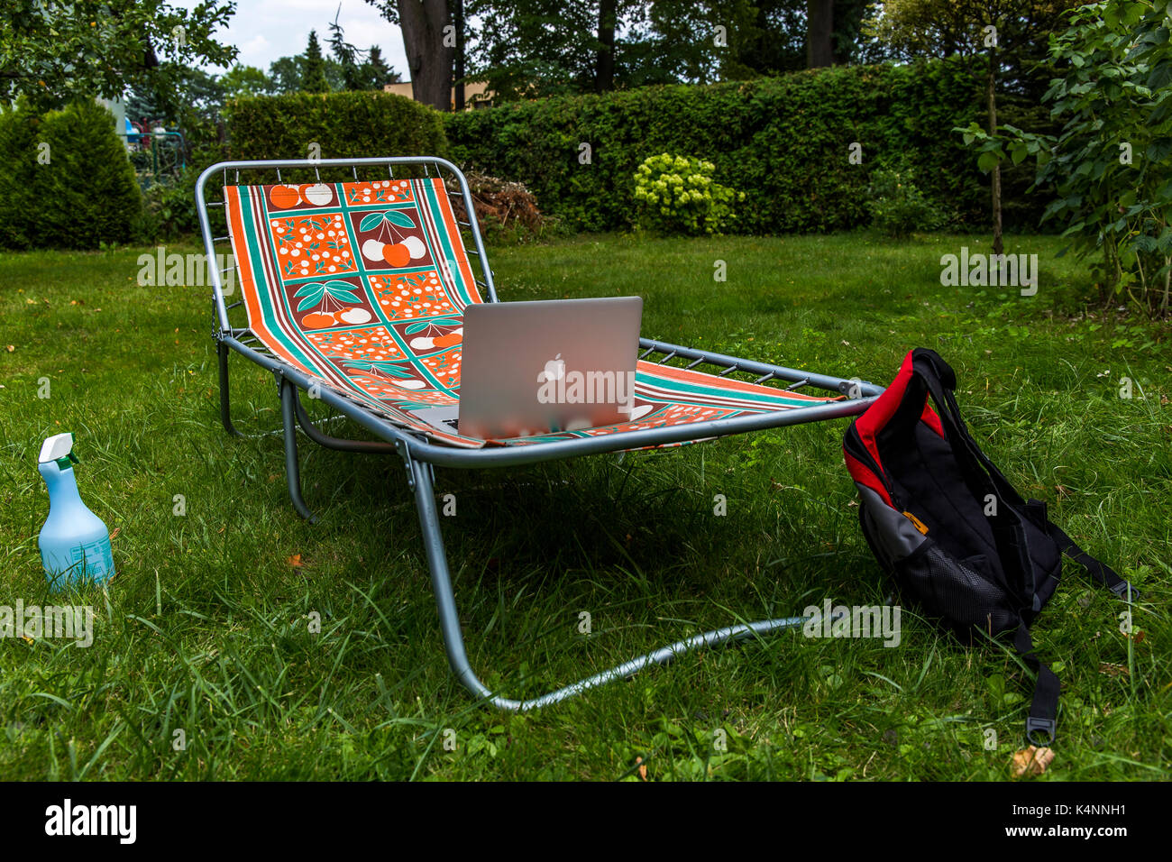 Sunbed on the grass with apple macbook on it and a bag. Stock Photo