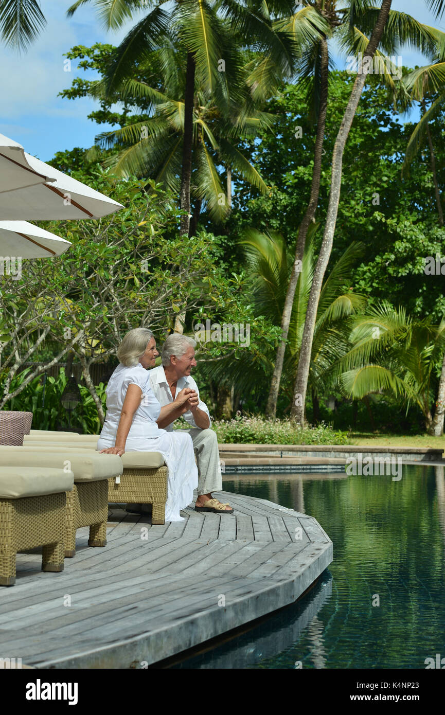 Smiling elderly couple sitting near swimming pool Stock Photo - Alamy
