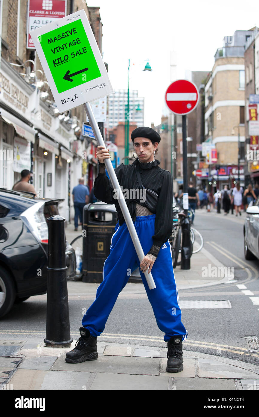 LONDON, ENGLAND - August 20, 2017 male promoter with an advertising poster stands in the middle of the pavement on Bricklane Stock Photo