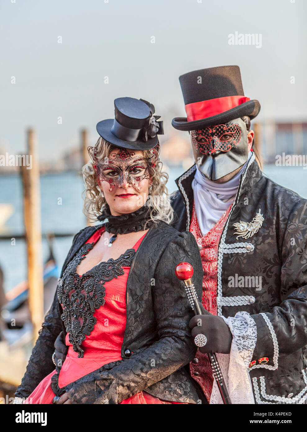 Venice, Italy- February 18th, 2012: Environmental portrait of an unidentified couple wearing black disguises and traditional Venetian masks during the Stock Photo