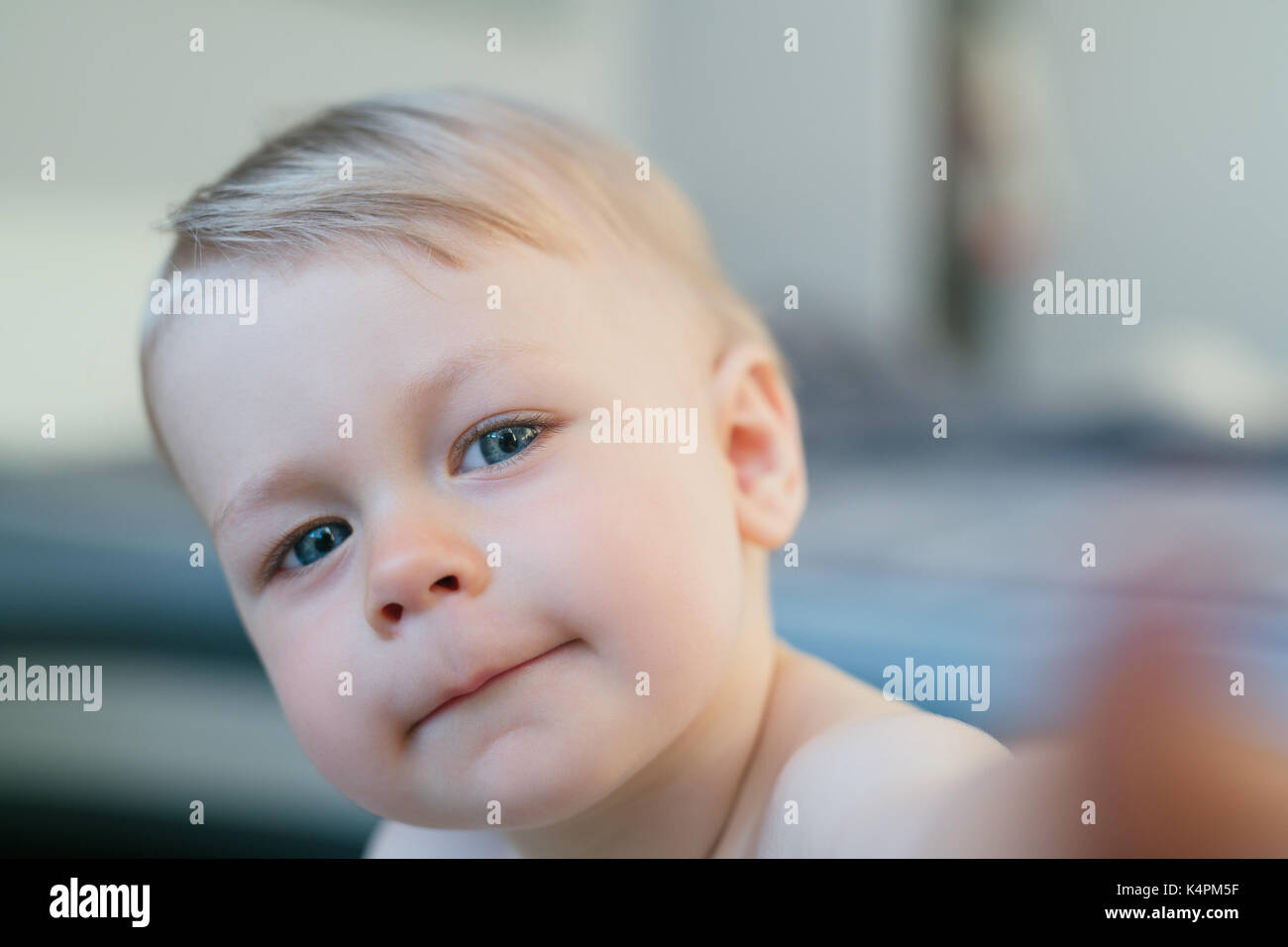 Curious one year child draw finger to camera in home interior. Focus on eye. Stock Photo