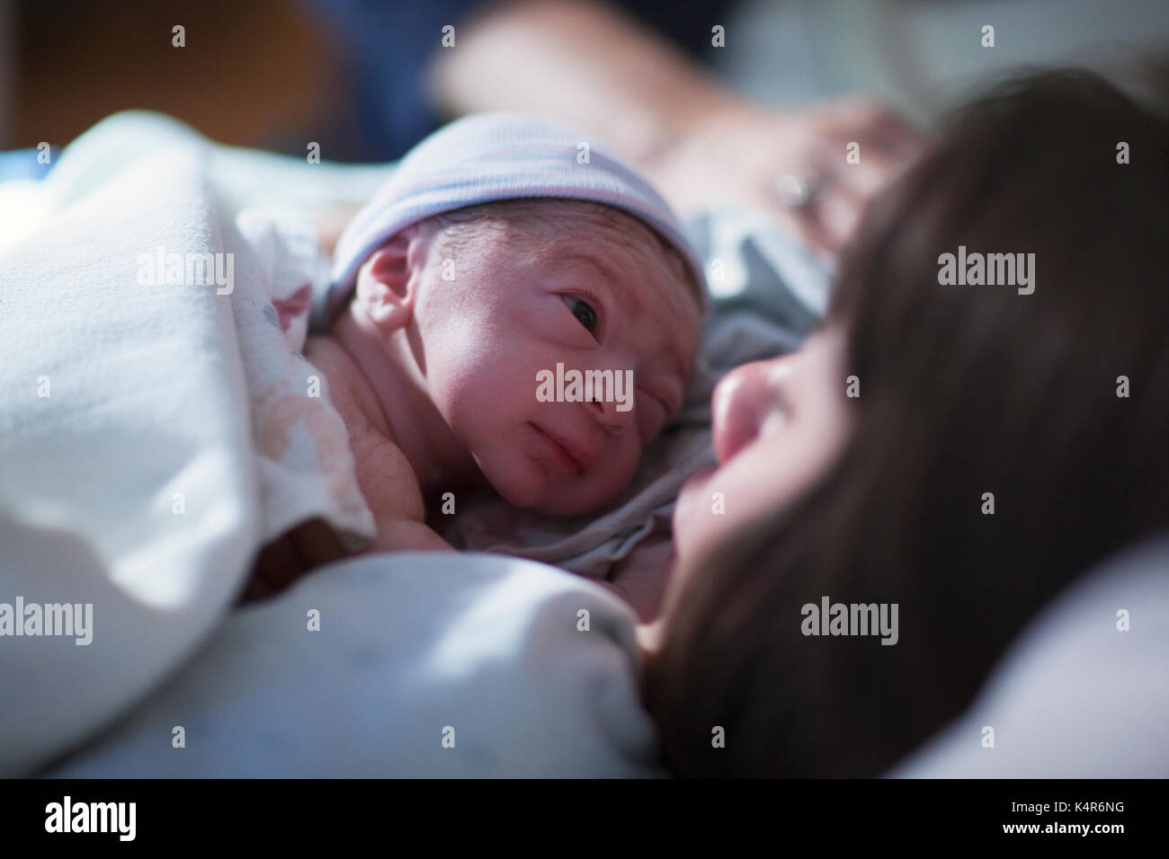 A newborn baby boy rest on his mother's chest and stares into her eyes