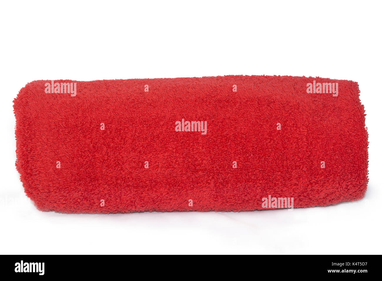 Red single towel rolled up against a plain white and isolating background. Stock Photo